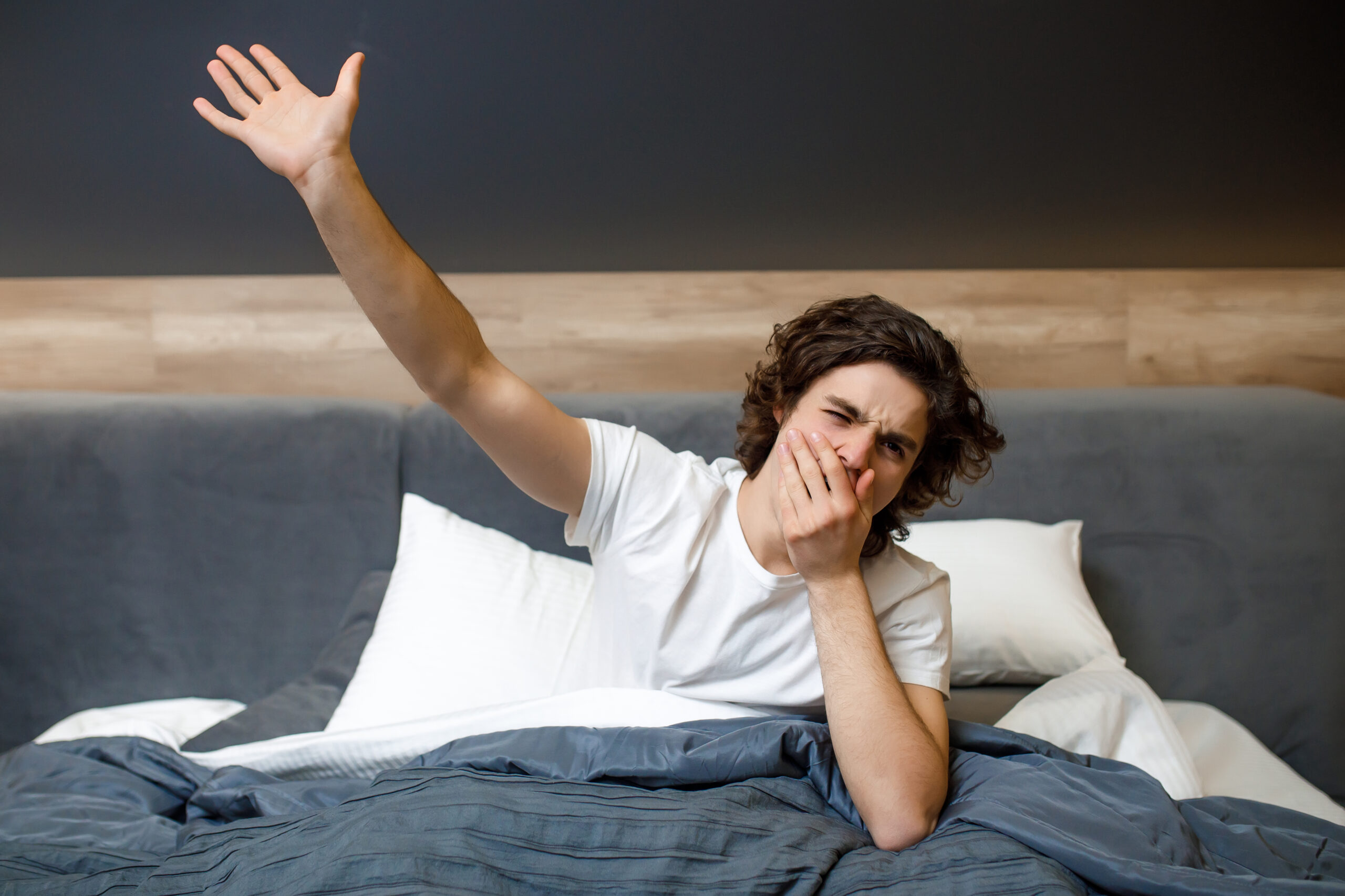 Image of a handsome young man in the morning yawning at weekend time.