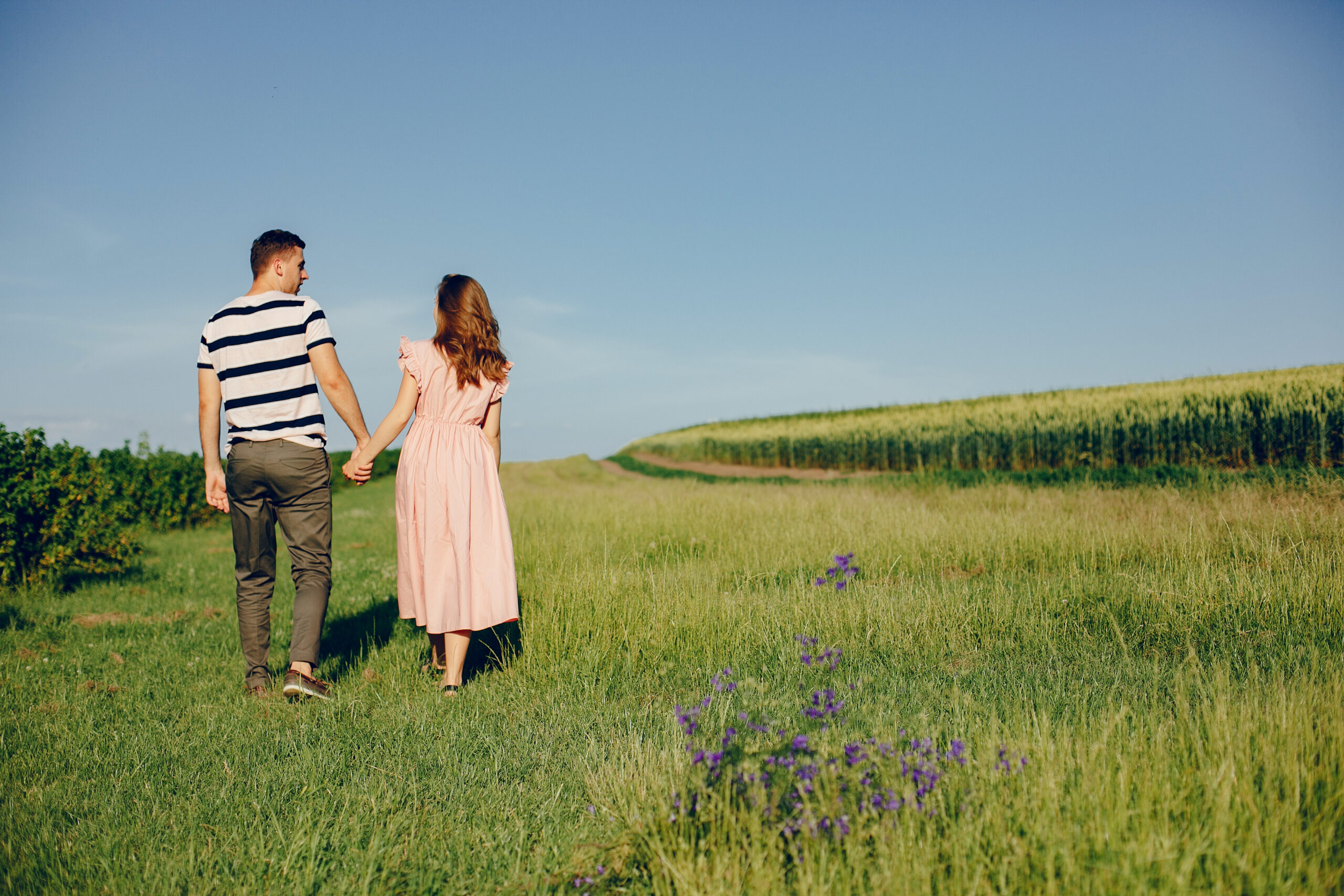 Couple in a field. Girl in a pink dress. Man in a white shirt