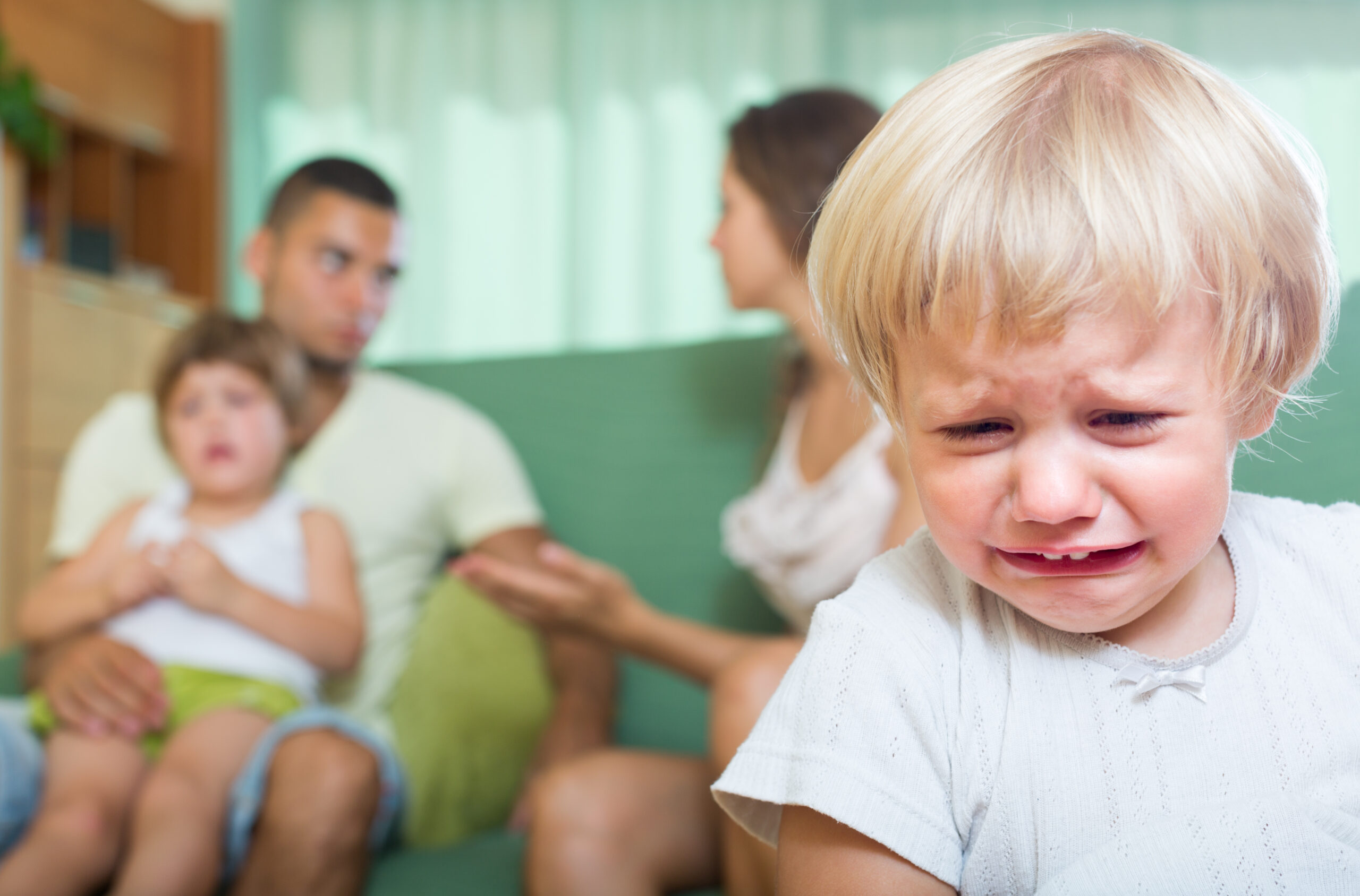 Young married couple with two little daughters having quarrel at home
